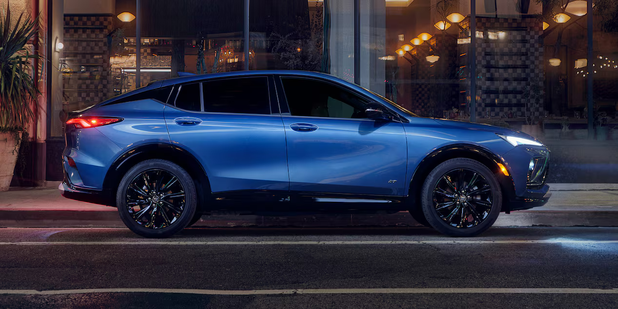 Blue Buick Envista parked on a city street at night.