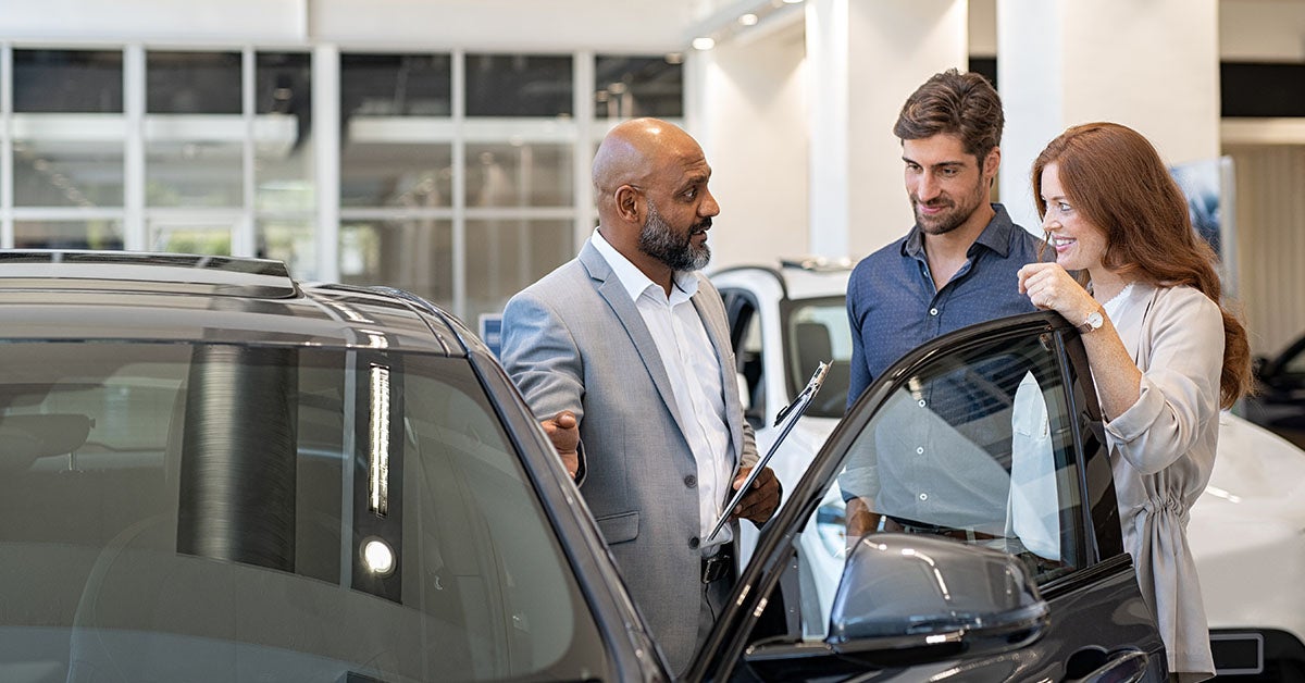 Buick customer service representative talking to couple in the model showroom.