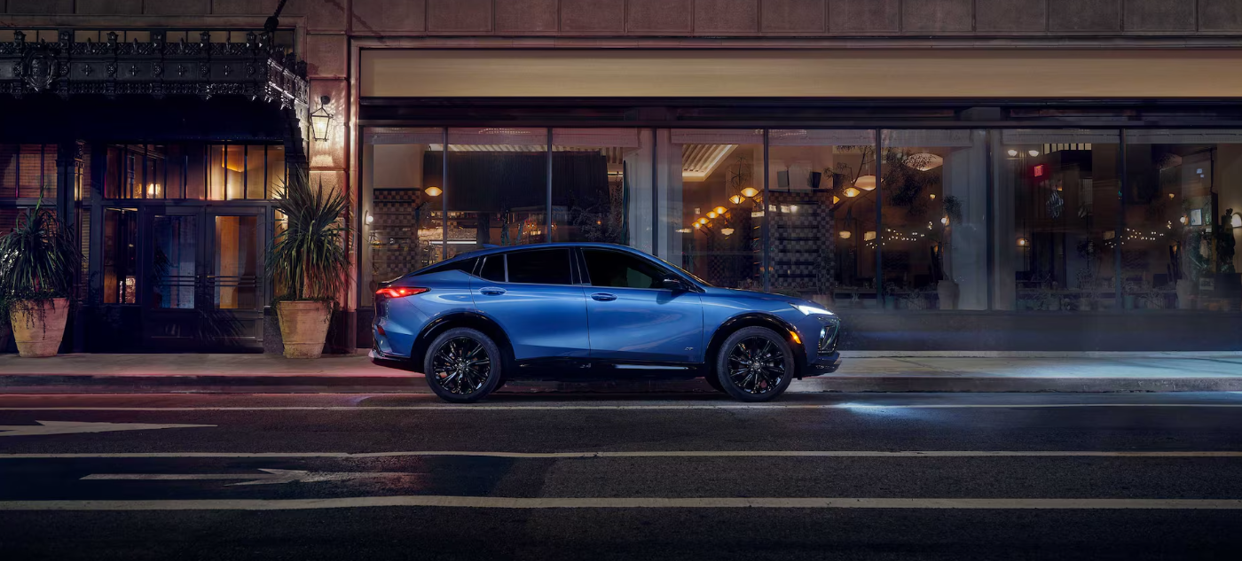 A blue 2026 Buick Envista parked on a city street at night.